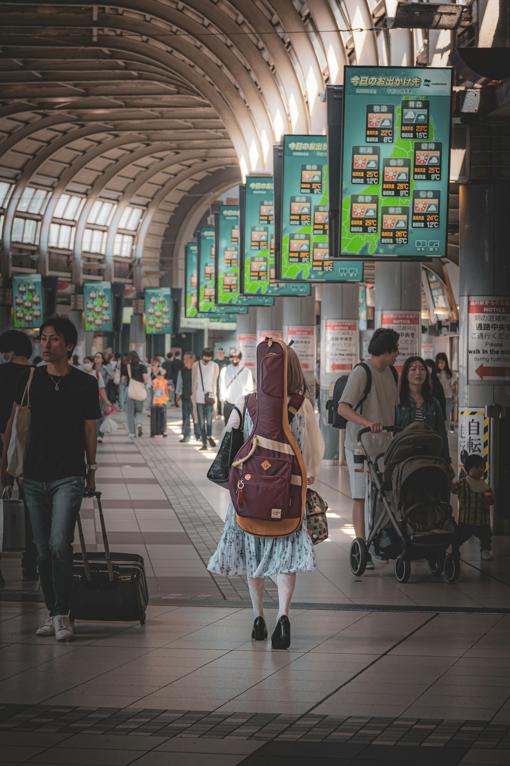 a woman walking through a train station carrying a suitcase