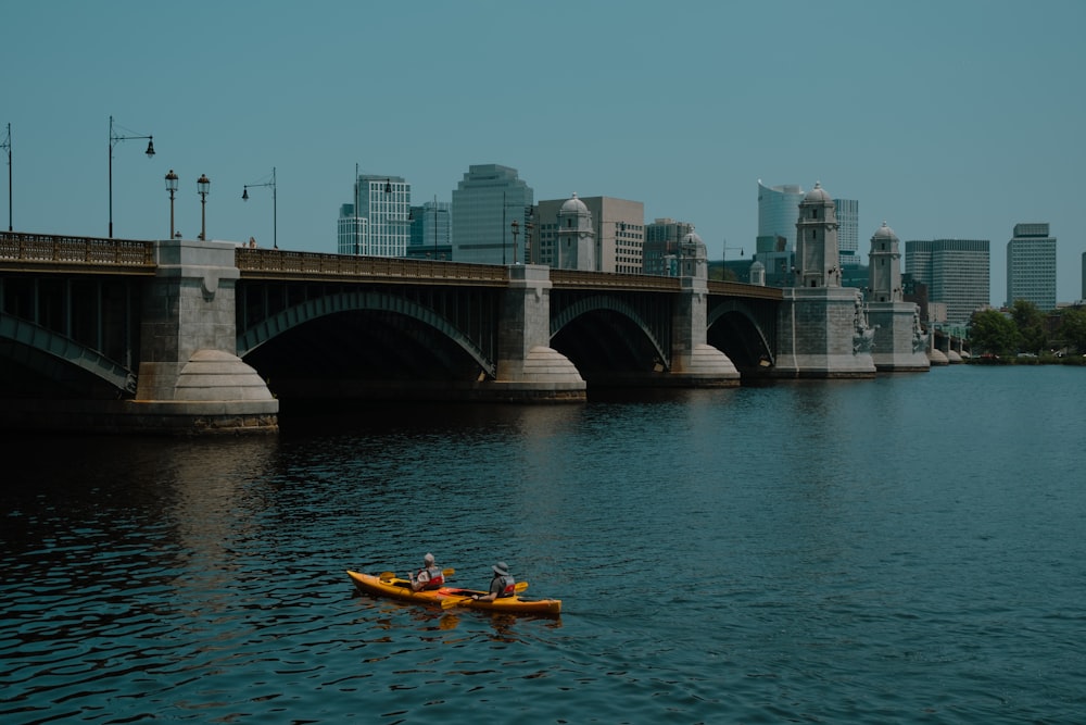 a person in a kayak on the water near a bridge