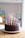 Close-up of a colorful layered birthday cake with delicate decorations on a rustic wooden table.