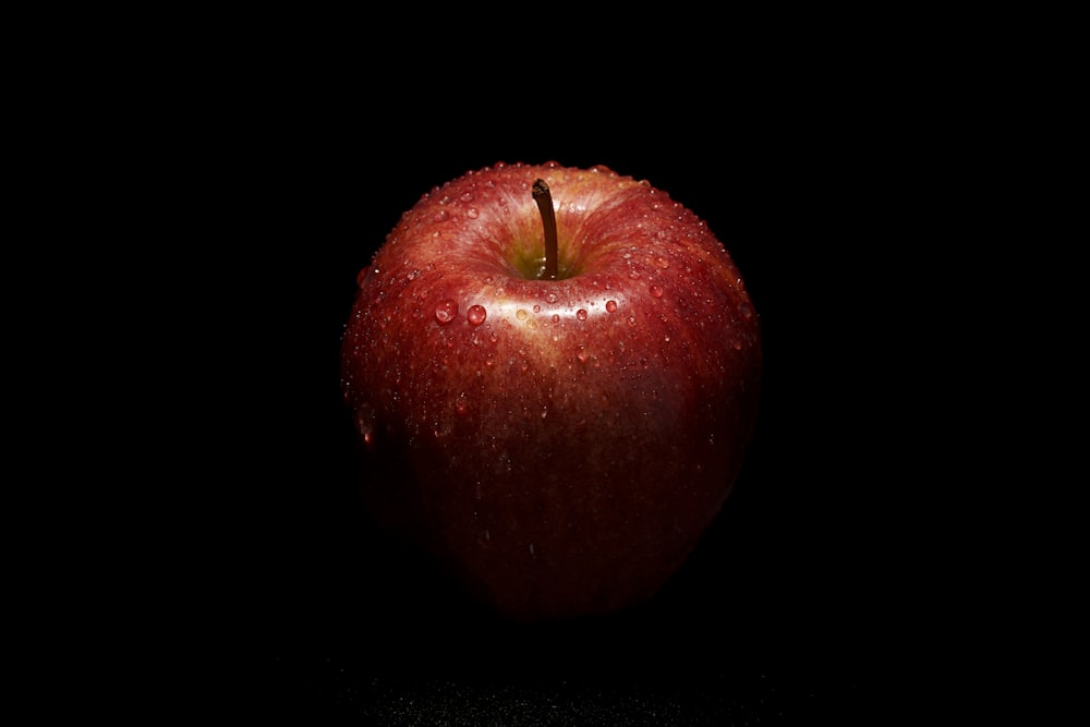 uma maçã vermelha sentada em cima de uma mesa preta