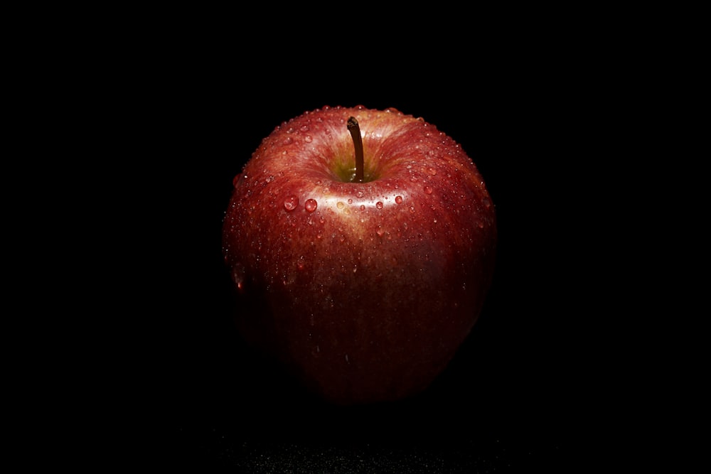 a red apple sitting on top of a black table