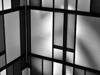 A geometric pattern of intersecting black lines and shaded rectangles creating an abstract grid-like design. The grayscale color scheme adds a modern and minimalistic feel.