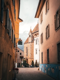 a narrow street with a church steeple in the background
