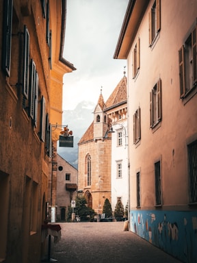 a narrow street with a church steeple in the background