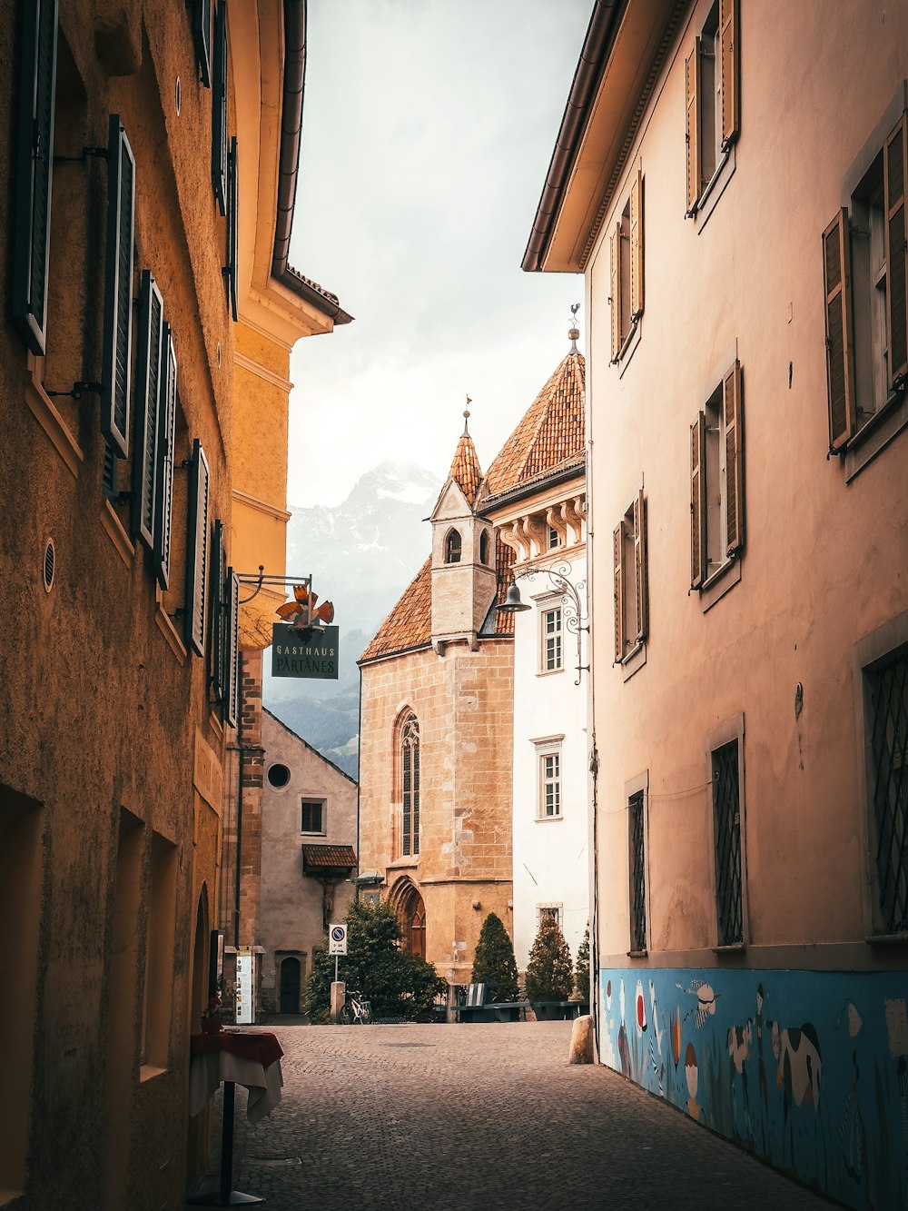 a narrow street with a church steeple in the background