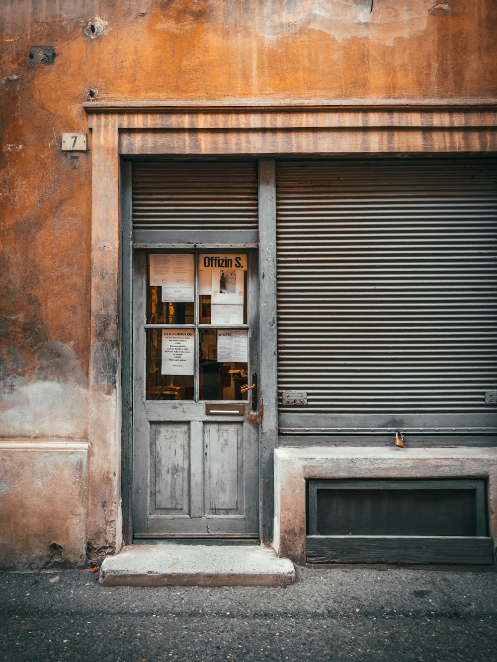 an old building with a closed door and a sign on the door