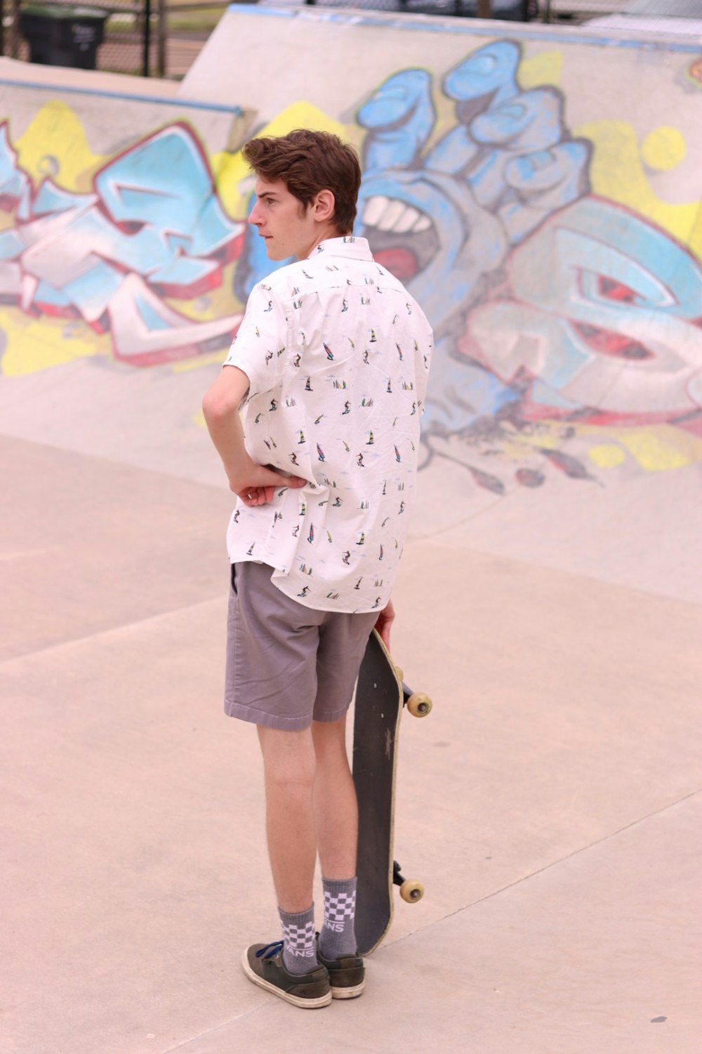 a young man holding a skateboard at a skate park
