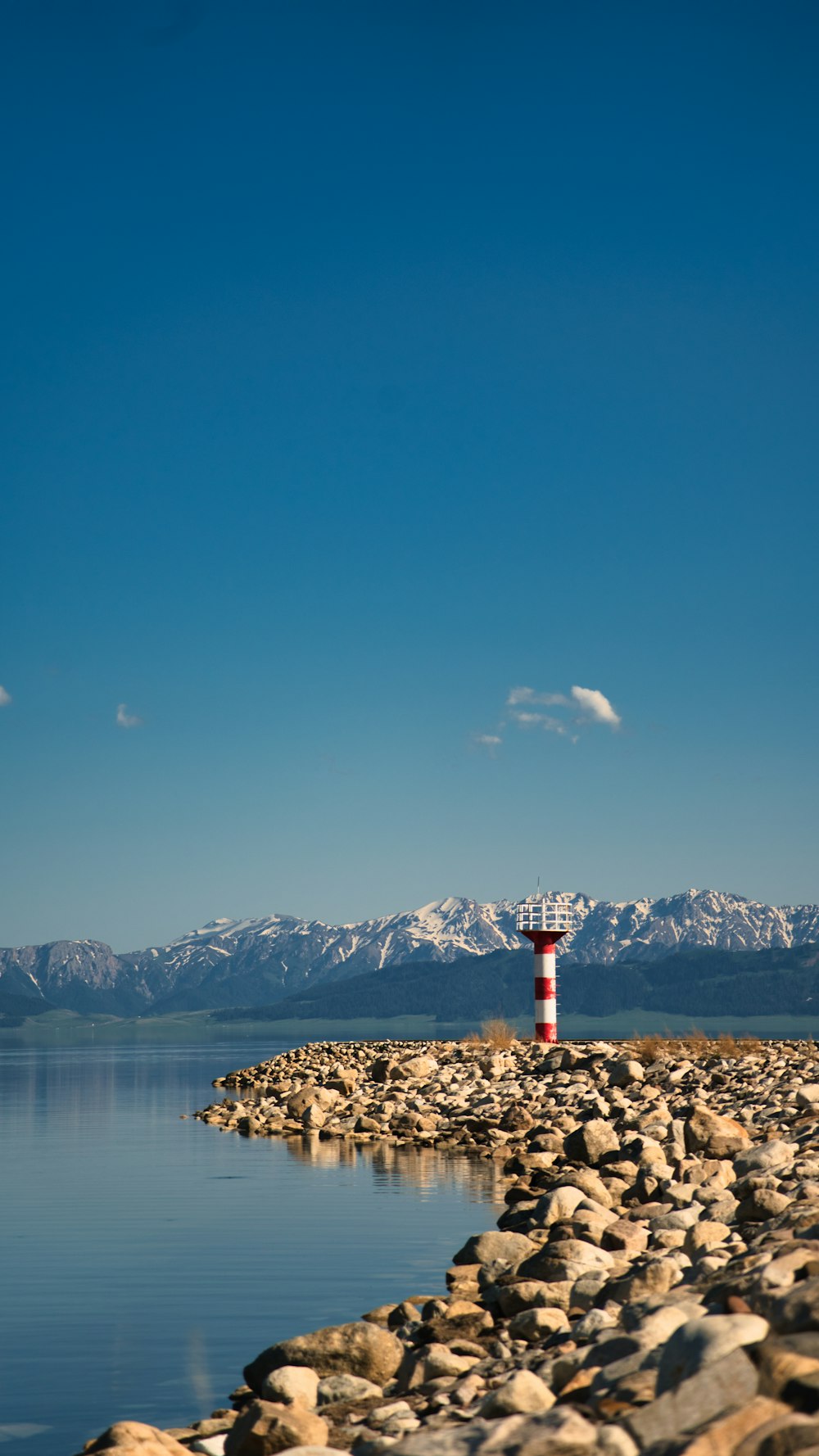 a lighthouse on a rocky shore with mountains in the background