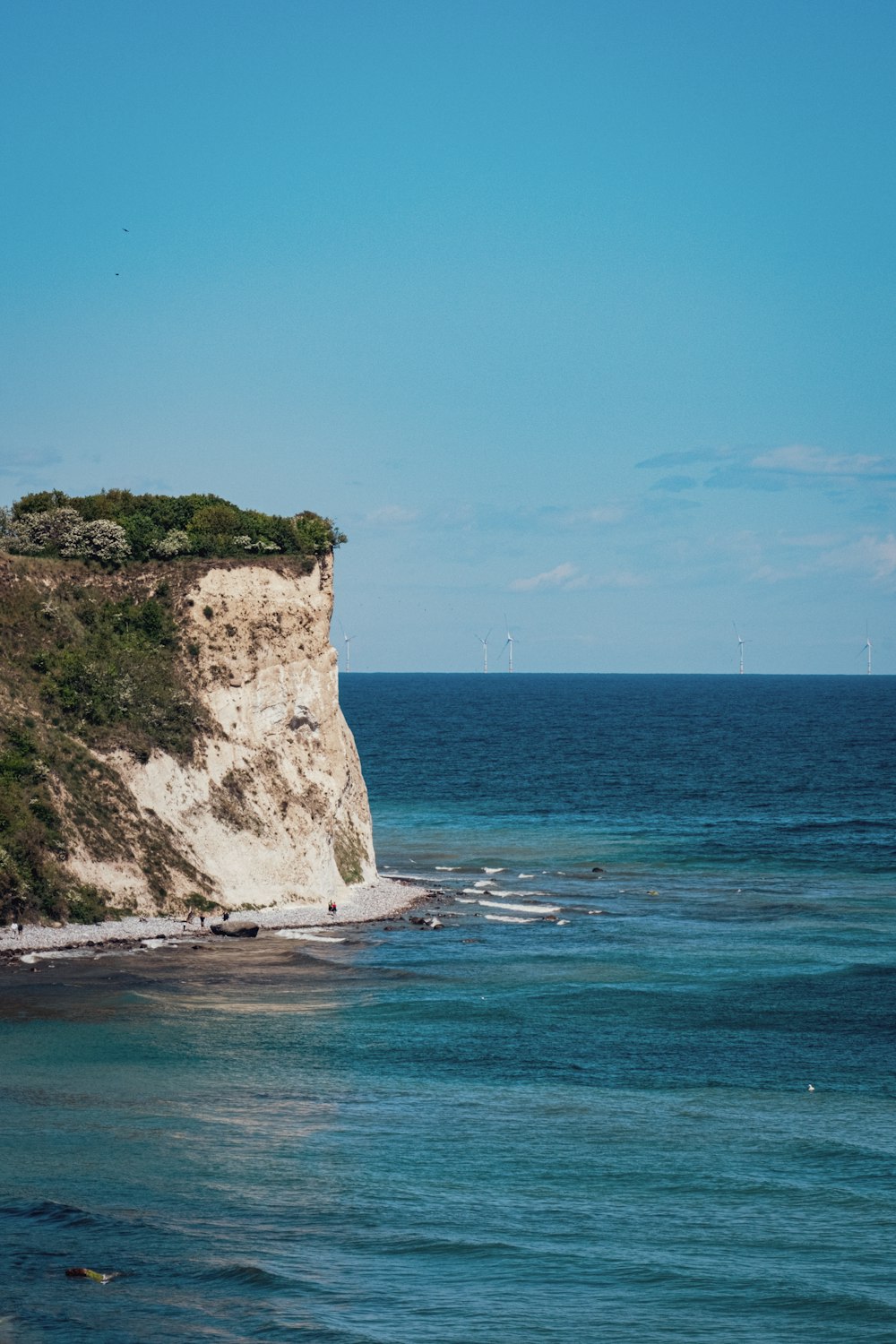 a large white cliff sitting on the side of a body of water