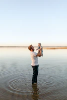 An instructor gently guiding a baby through water acclimation exercises.