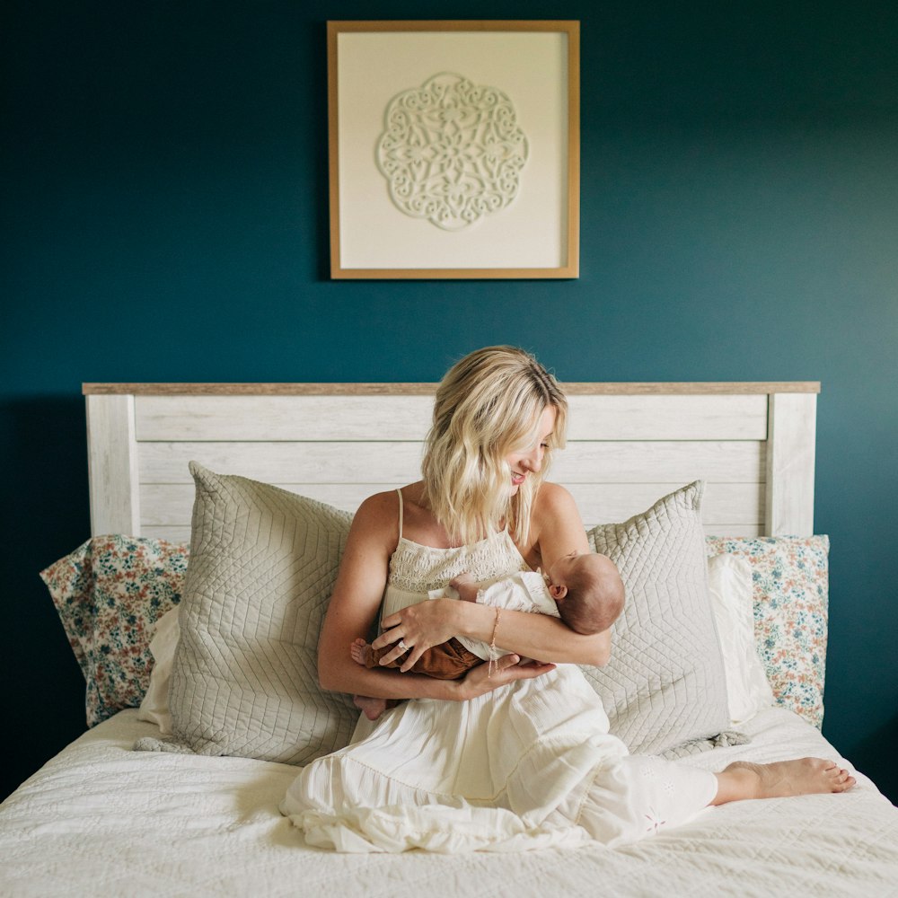una donna seduta su un letto che tiene in braccio un bambino