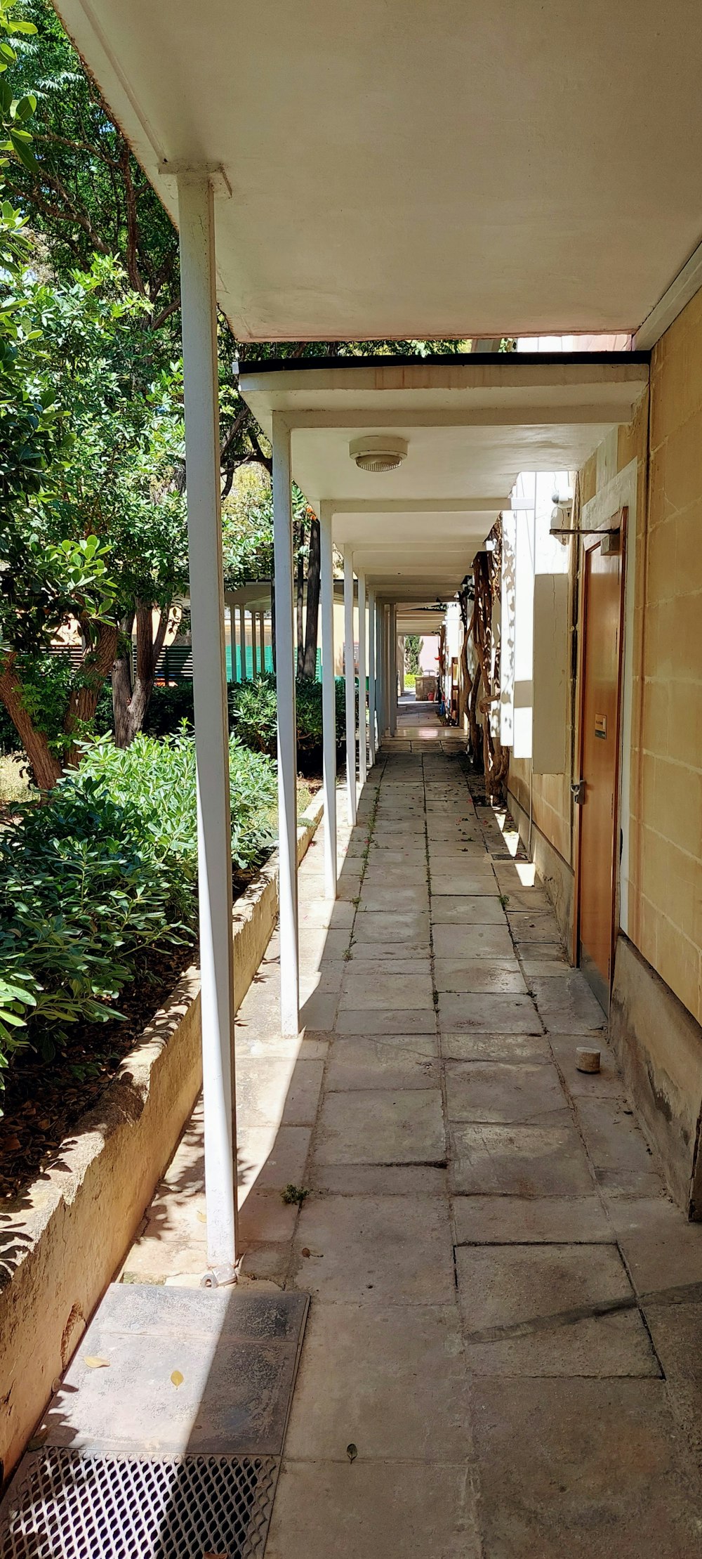 a long walkway between two buildings with white pillars