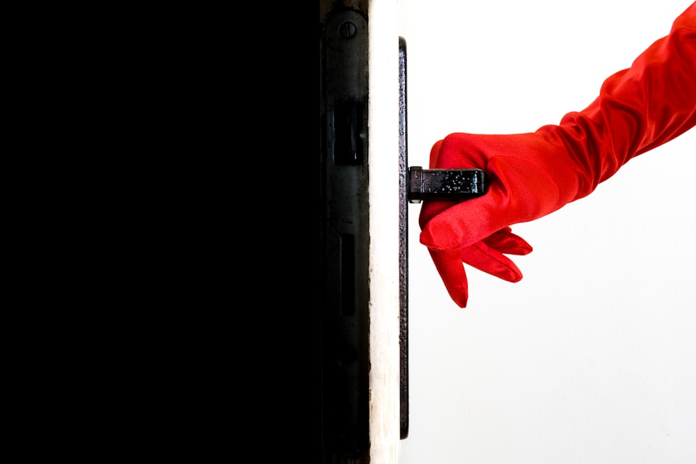 Eine Person in roten Handschuhen öffnet eine Tür