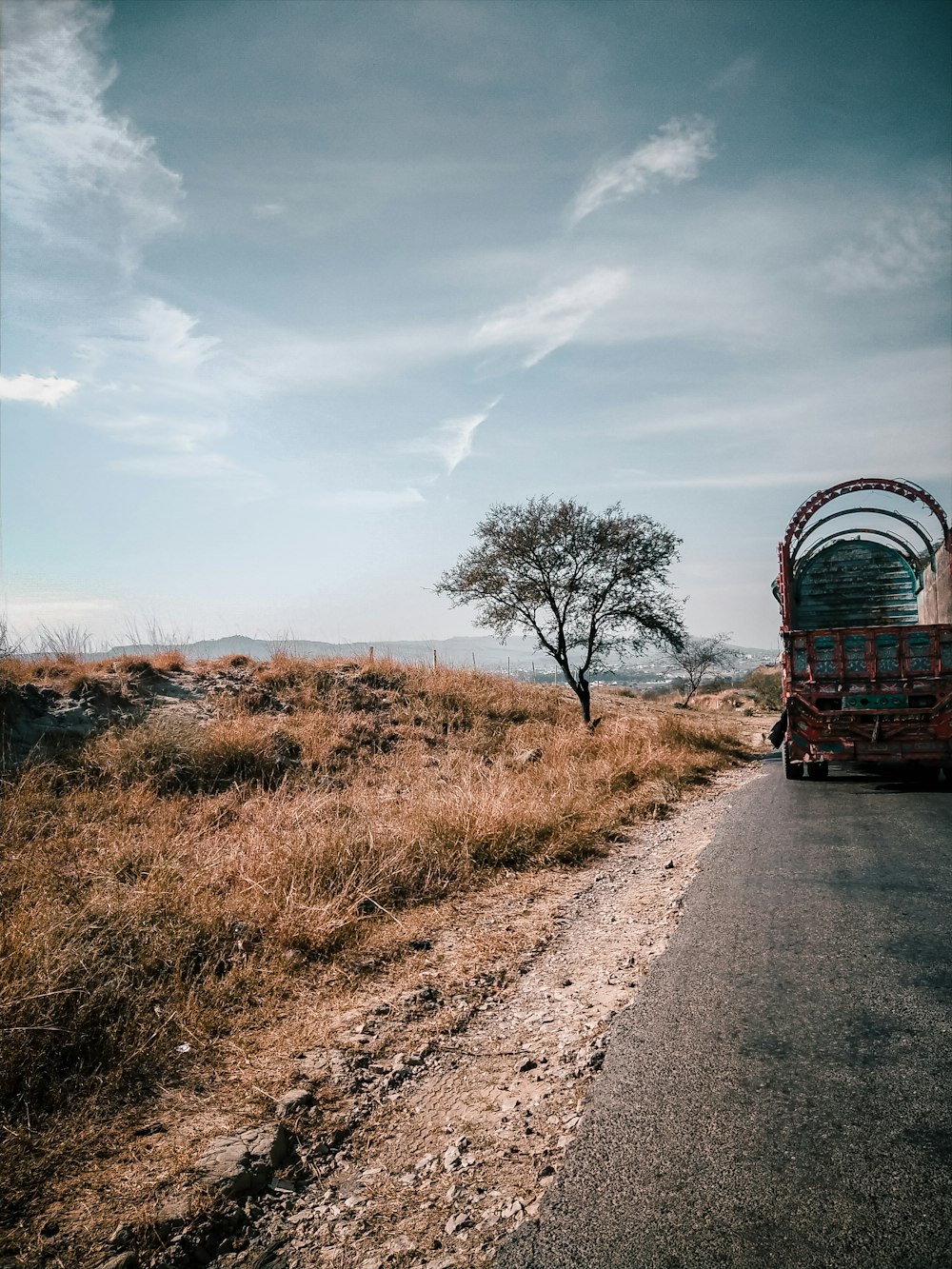 a truck driving down a road next to a tree