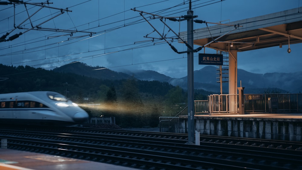 a white train traveling past a train station