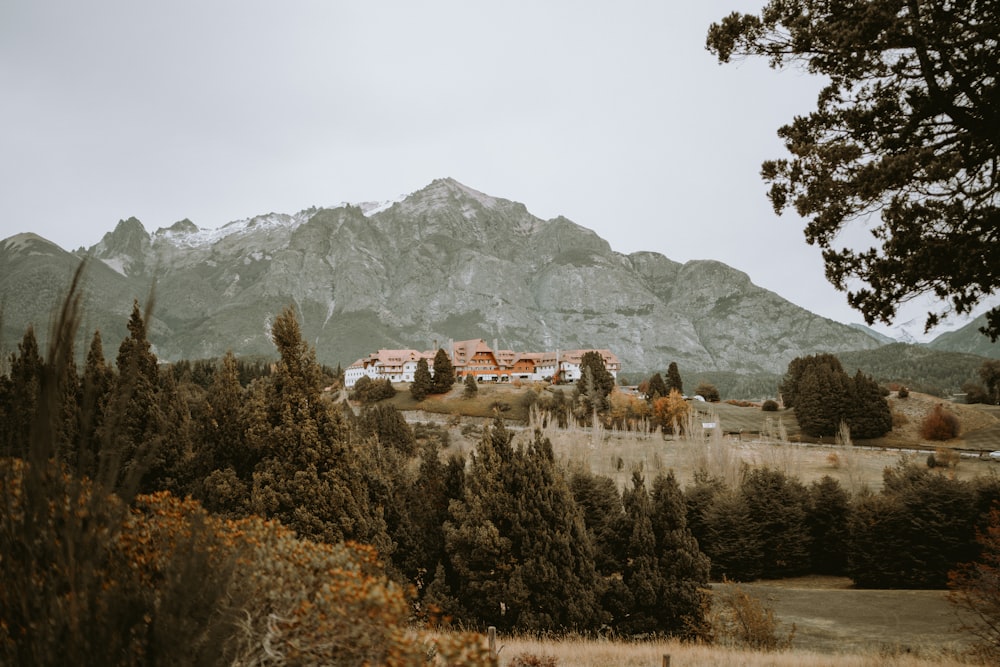 a house in the middle of a field with mountains in the background