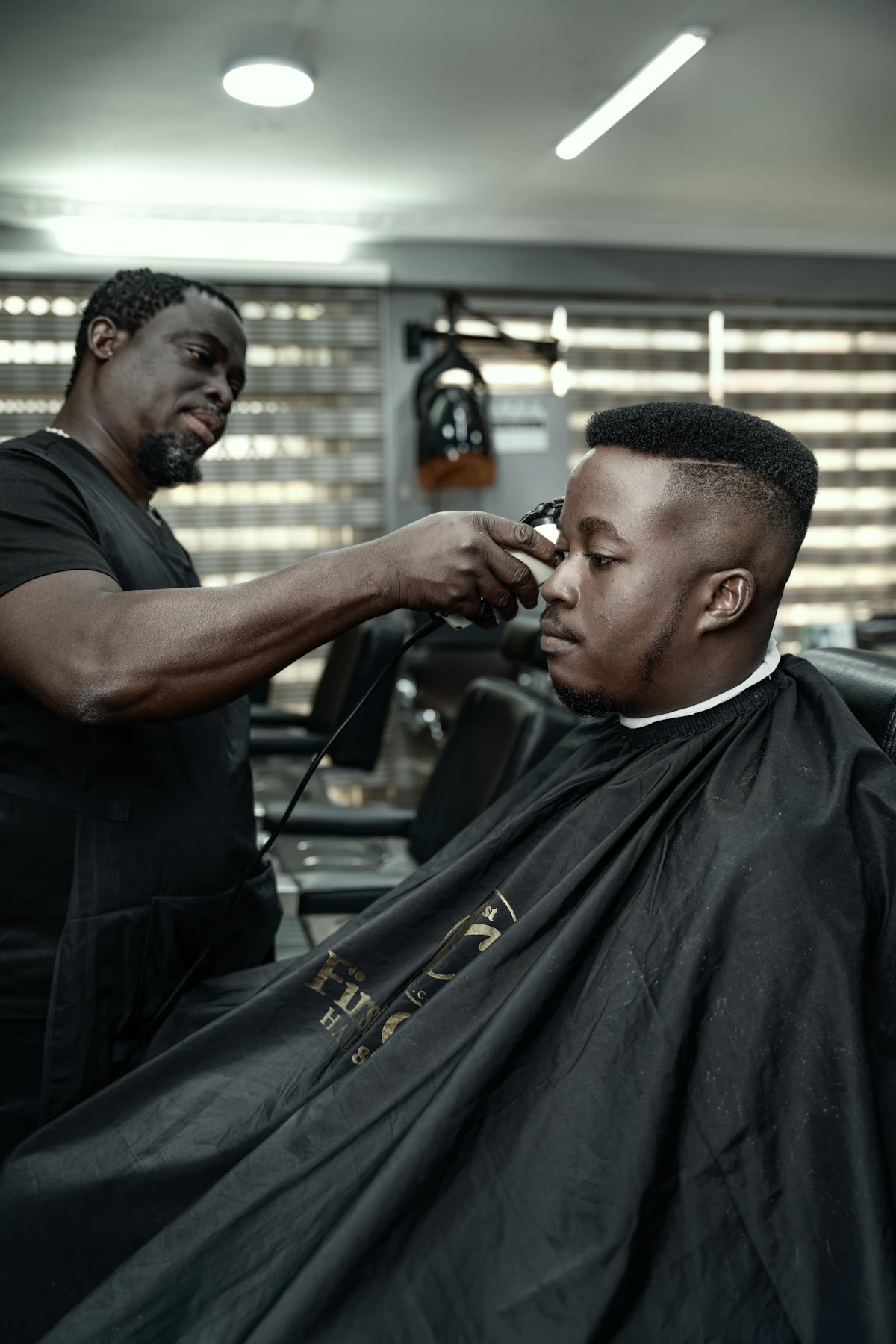 A Black barber finishing a precise flat-top fade