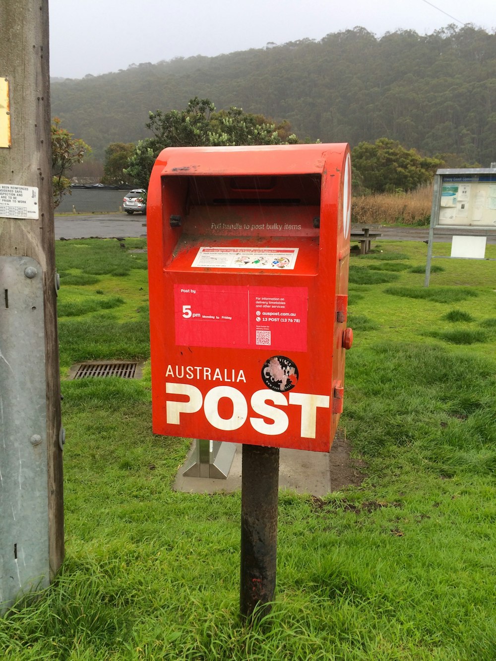 a red mailbox sitting on top of a lush green field