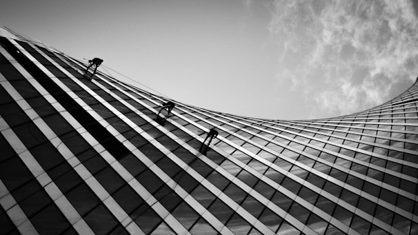 A skilled technician inspecting a modern building facade under moody lighting.