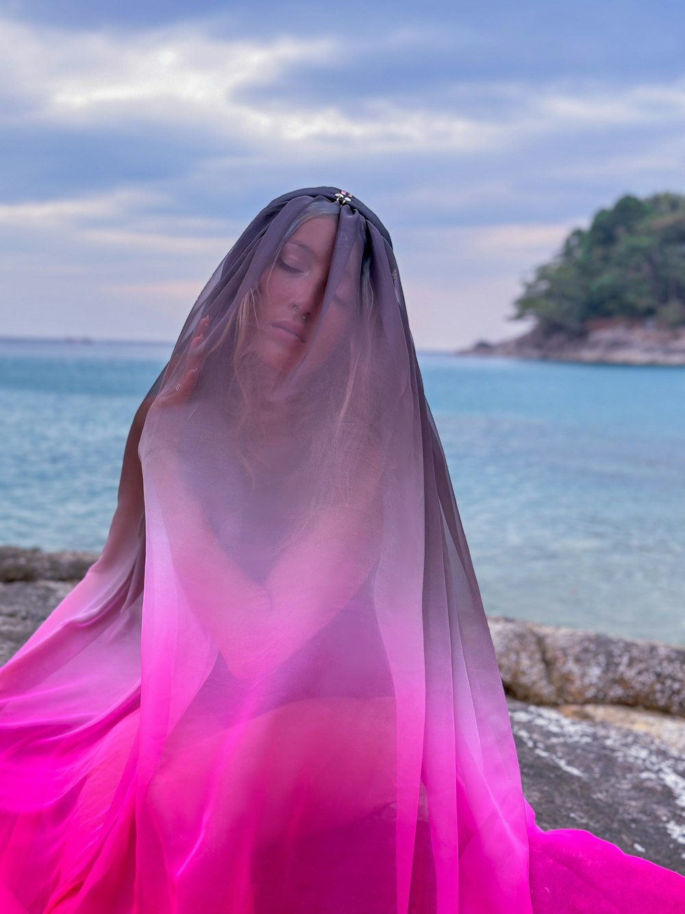 a woman wearing a veil standing on a beach