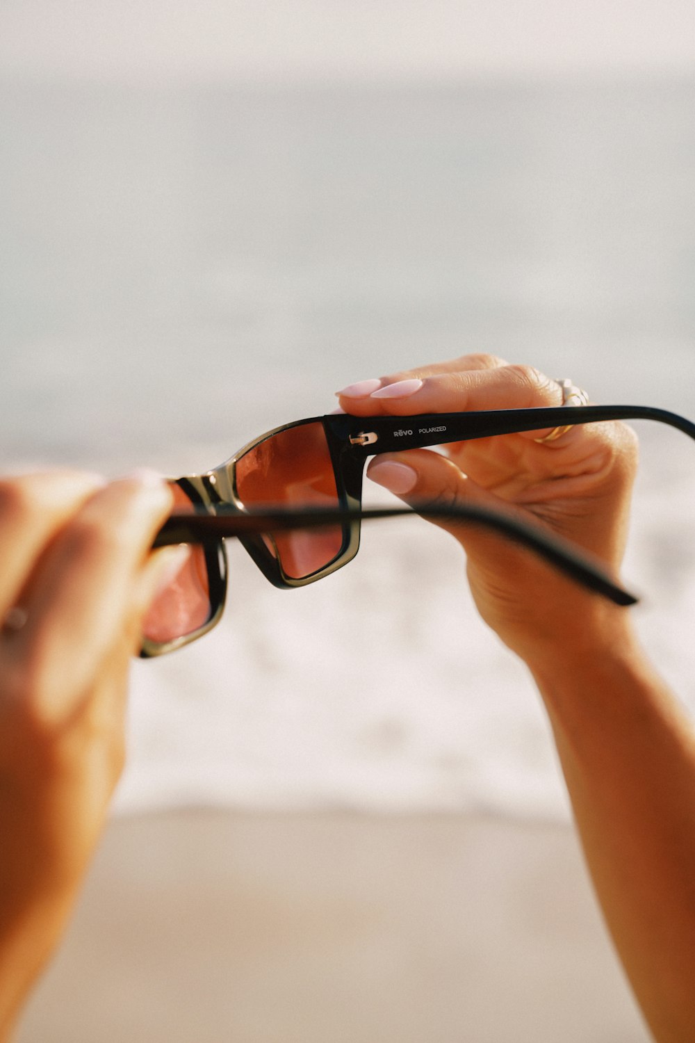 a pair of hands holding a pair of black sunglasses