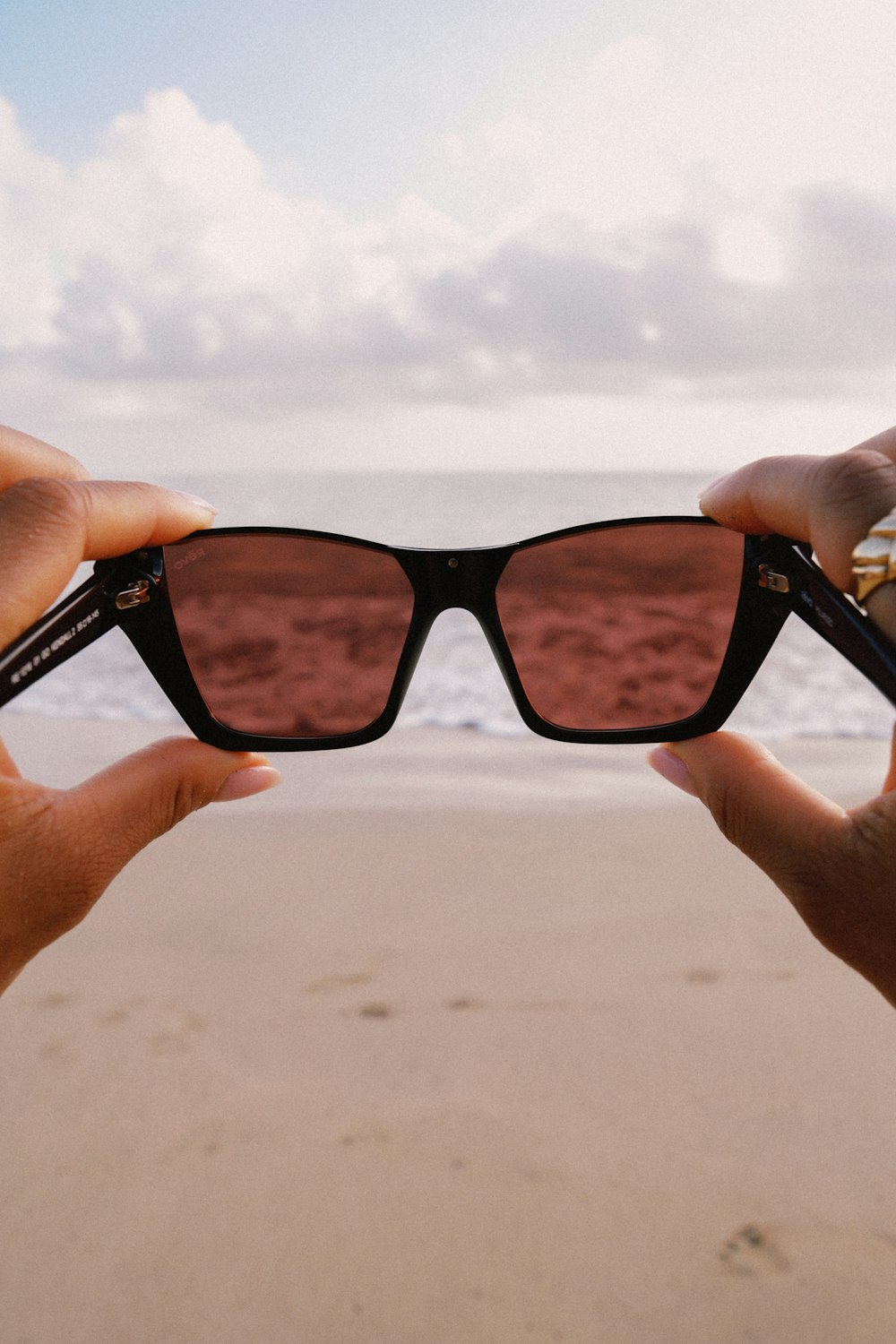 a pair of hands holding up a pair of sunglasses