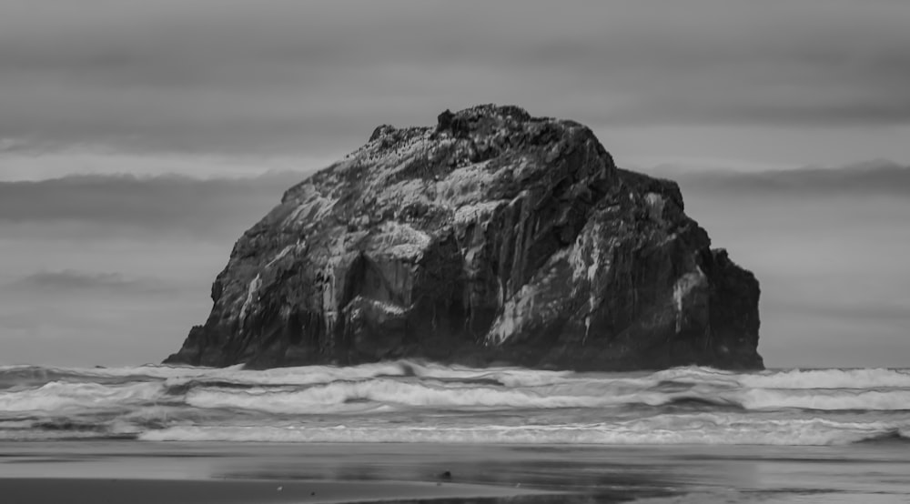Uma foto em preto e branco de uma rocha no oceano