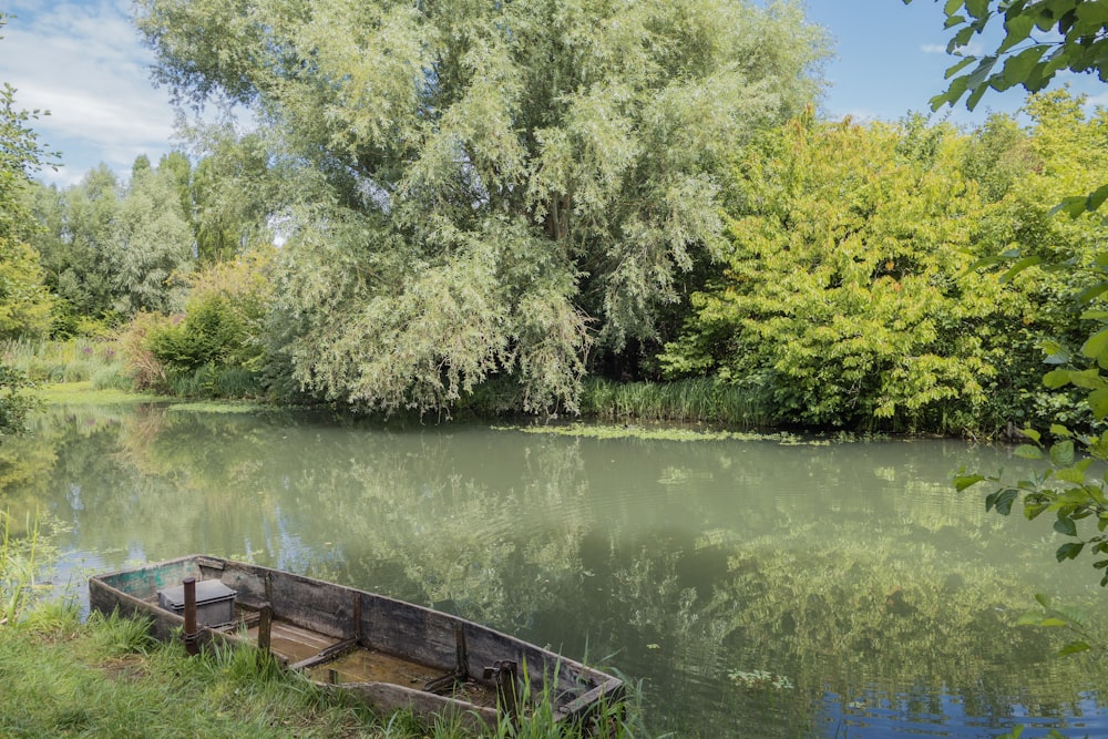 a small boat sitting on top of a river next to a lush green forest