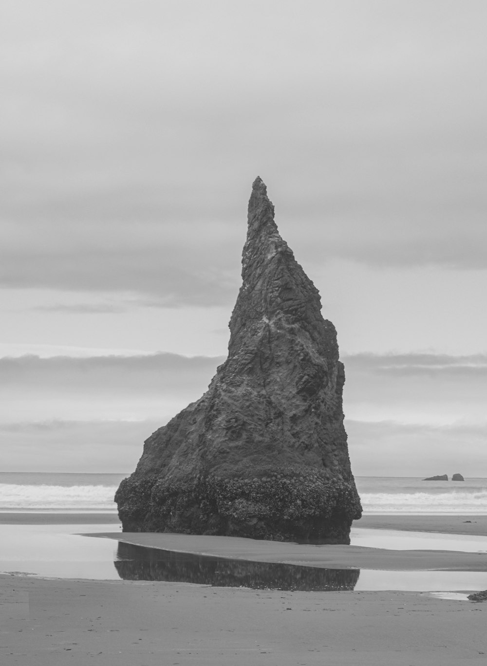 a rock sticking out of the sand on a beach