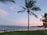 A scenic view of a beach with clear blue water and a sunset in the background.