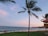 A scenic view of a beach with clear blue water and a sunset in the background.