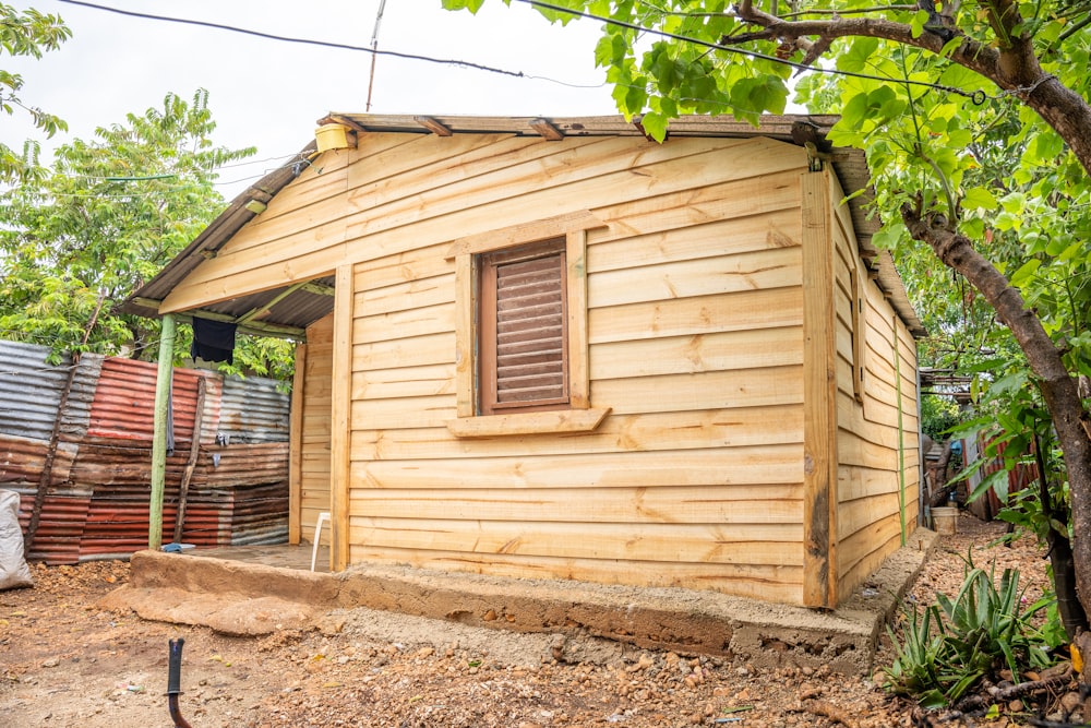 Un piccolo edificio di legno seduto accanto a un albero