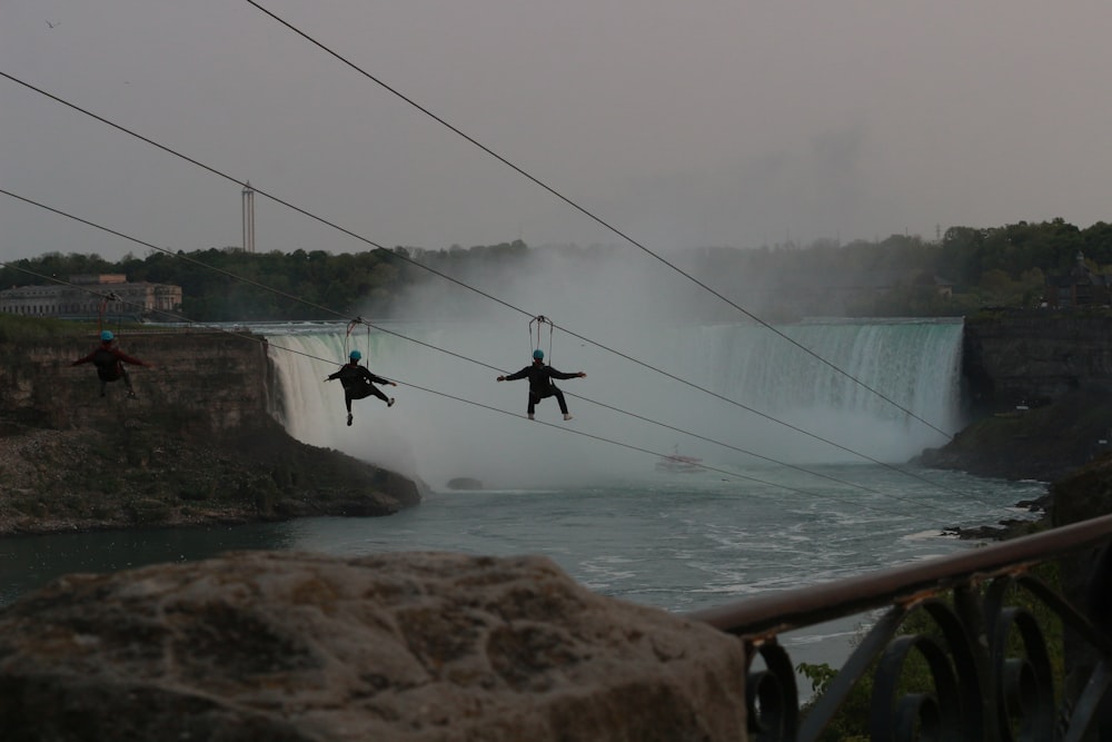a group of people hanging from wires above a river