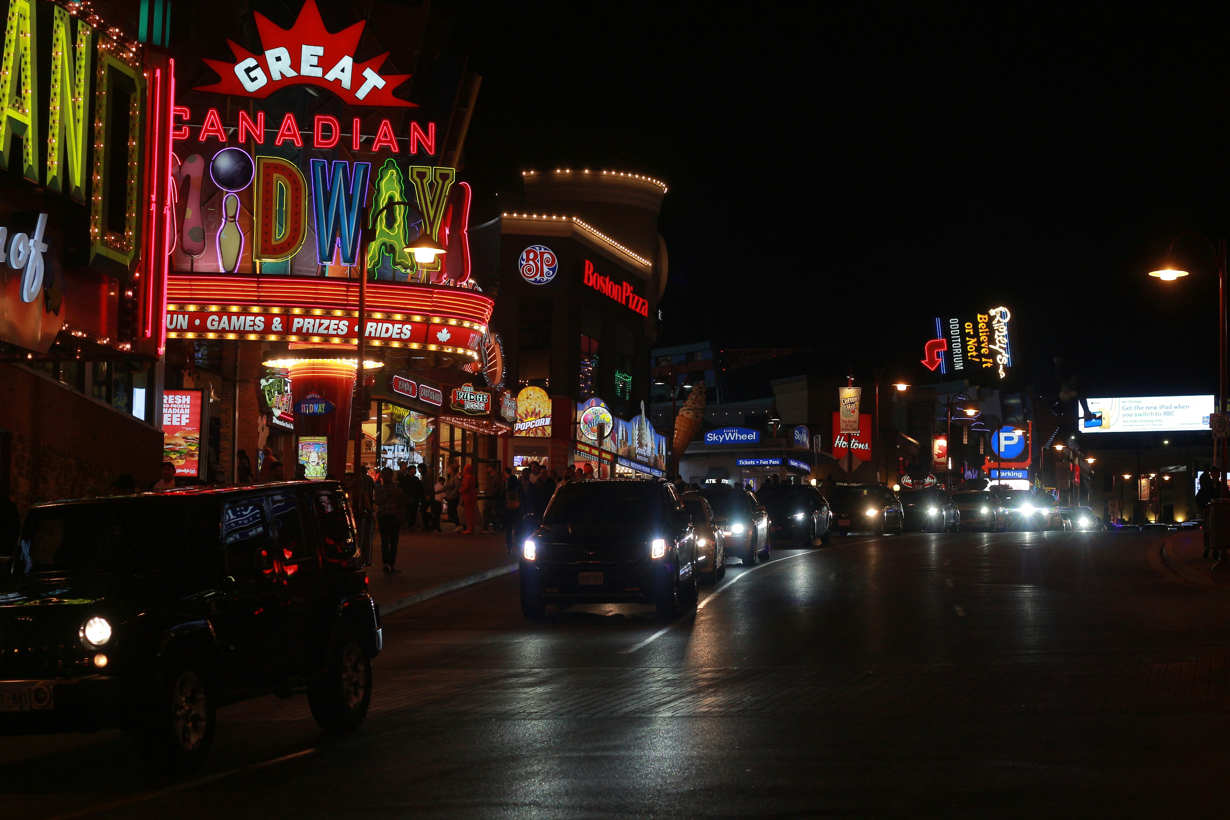 A city street at night with cars and neon signs photo – Free Car Image ...