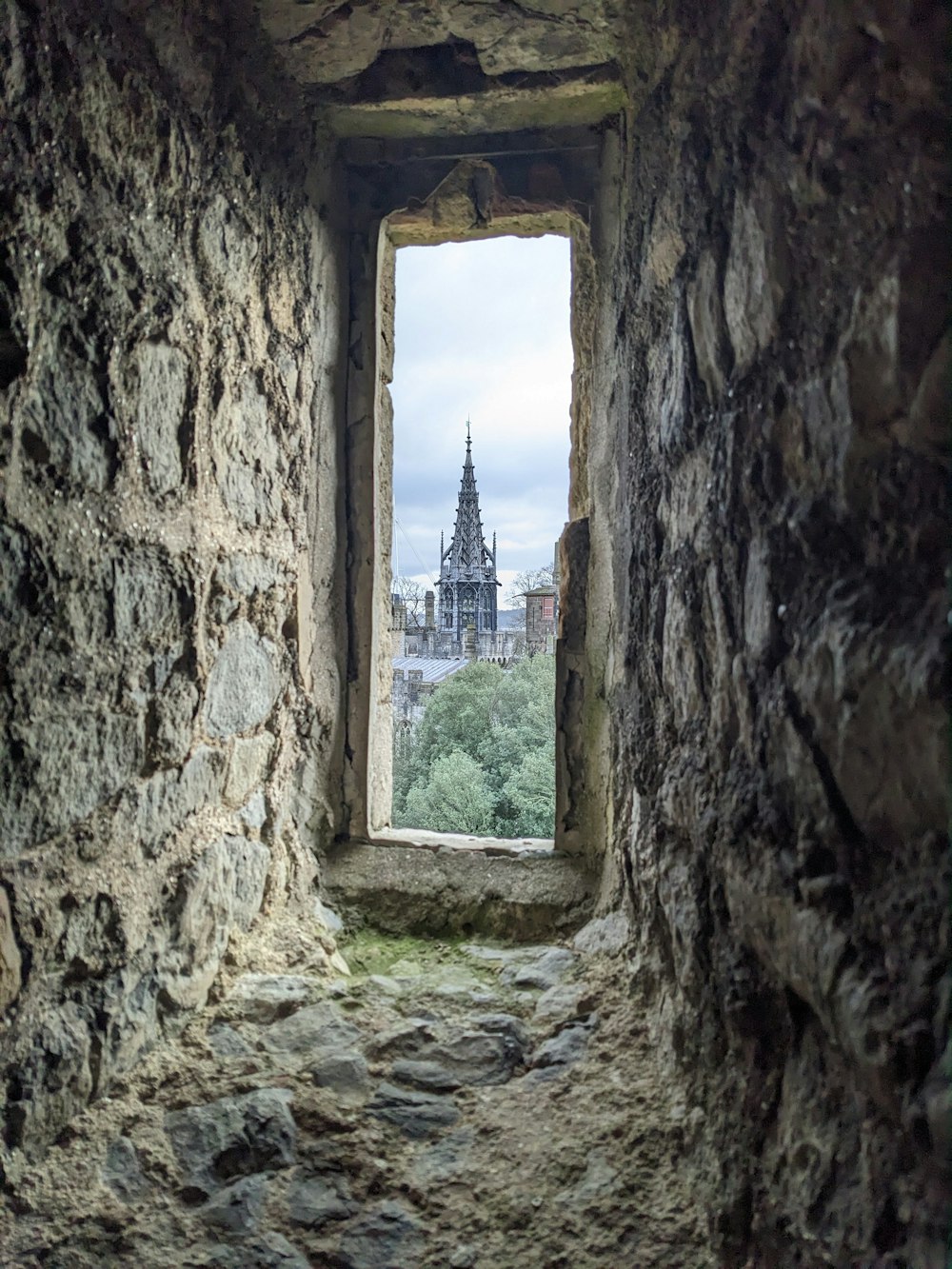 a window in a stone wall with a view of a city