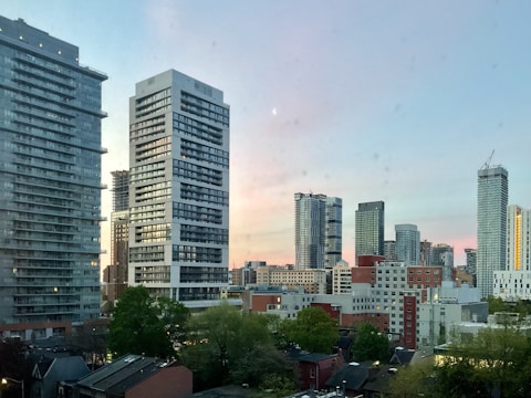 City skyline at sunset with modern buildings and clear sky.