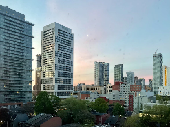 A city skyline at sunset with modern high-rise buildings representing urban real estate.