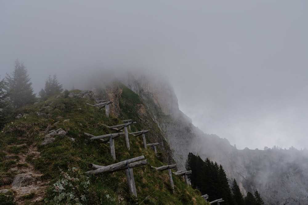 a foggy mountain with a bunch of wooden crosses on the side