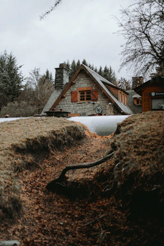 a house in the middle of a field with snow on the ground