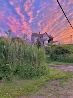 A warm, inviting exterior shot of Rusty Estate at sunset, highlighting the rustic-modern design and lush surroundings.