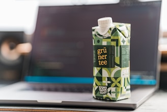 a carton of green tea sitting on top of a laptop