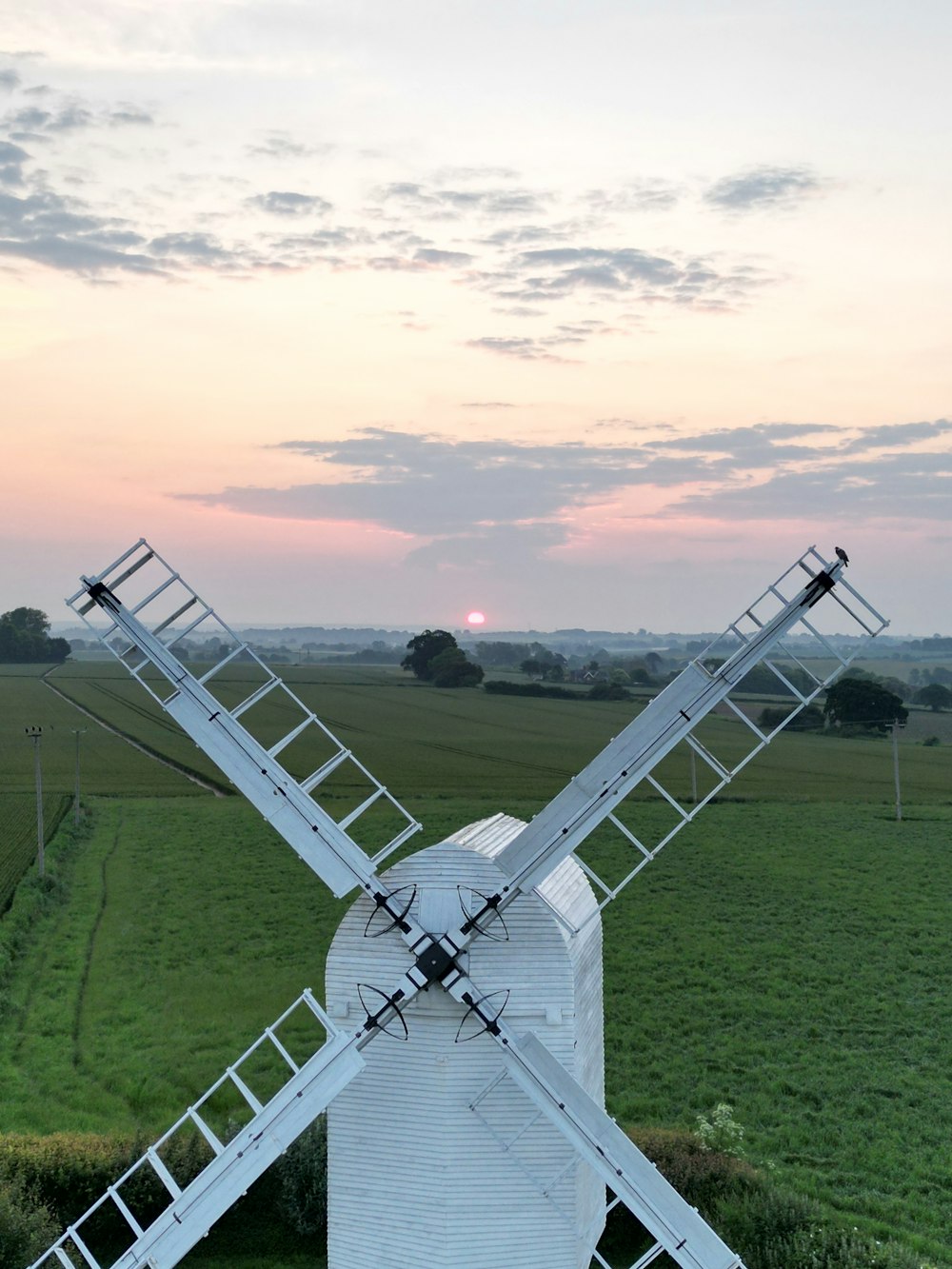 a windmill in a field with a sunset in the background