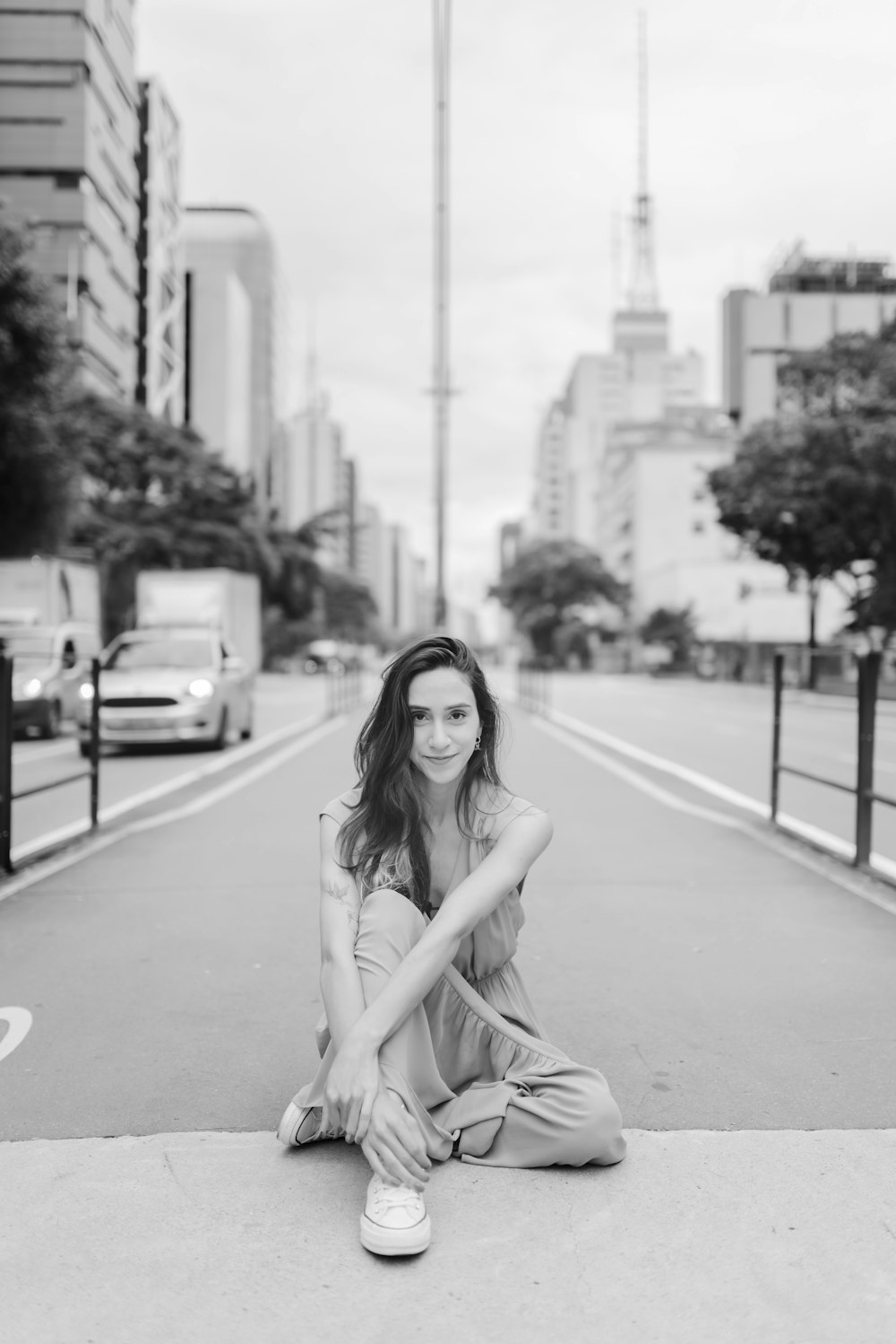 a black and white photo of a woman sitting on the side of a road