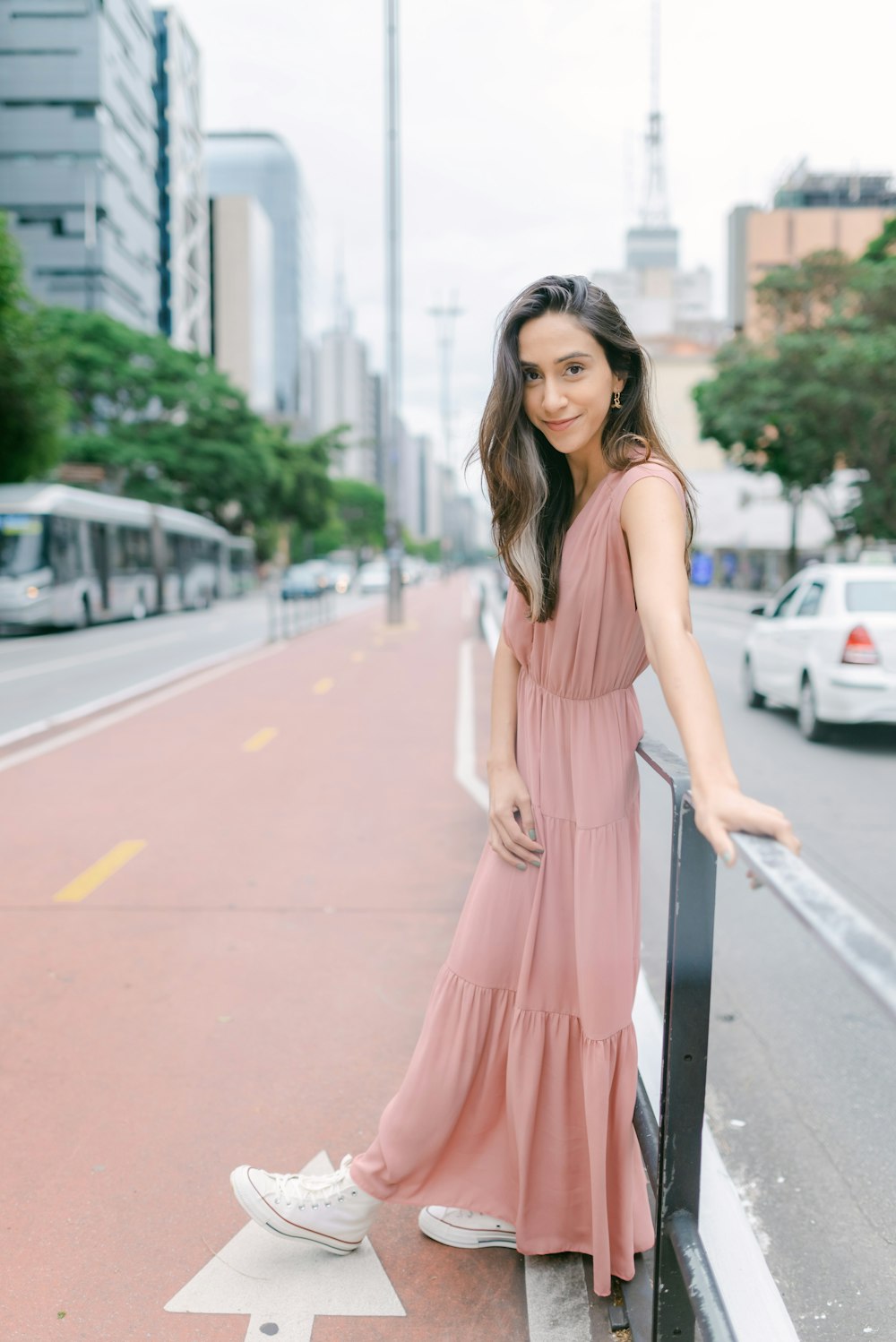 a woman in a pink dress leaning on a rail