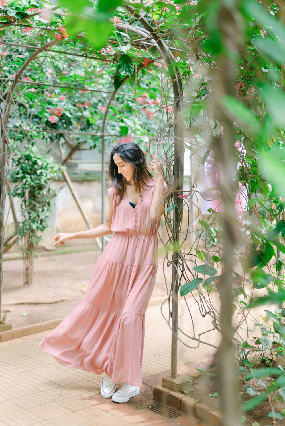 a woman in a pink dress standing in a garden