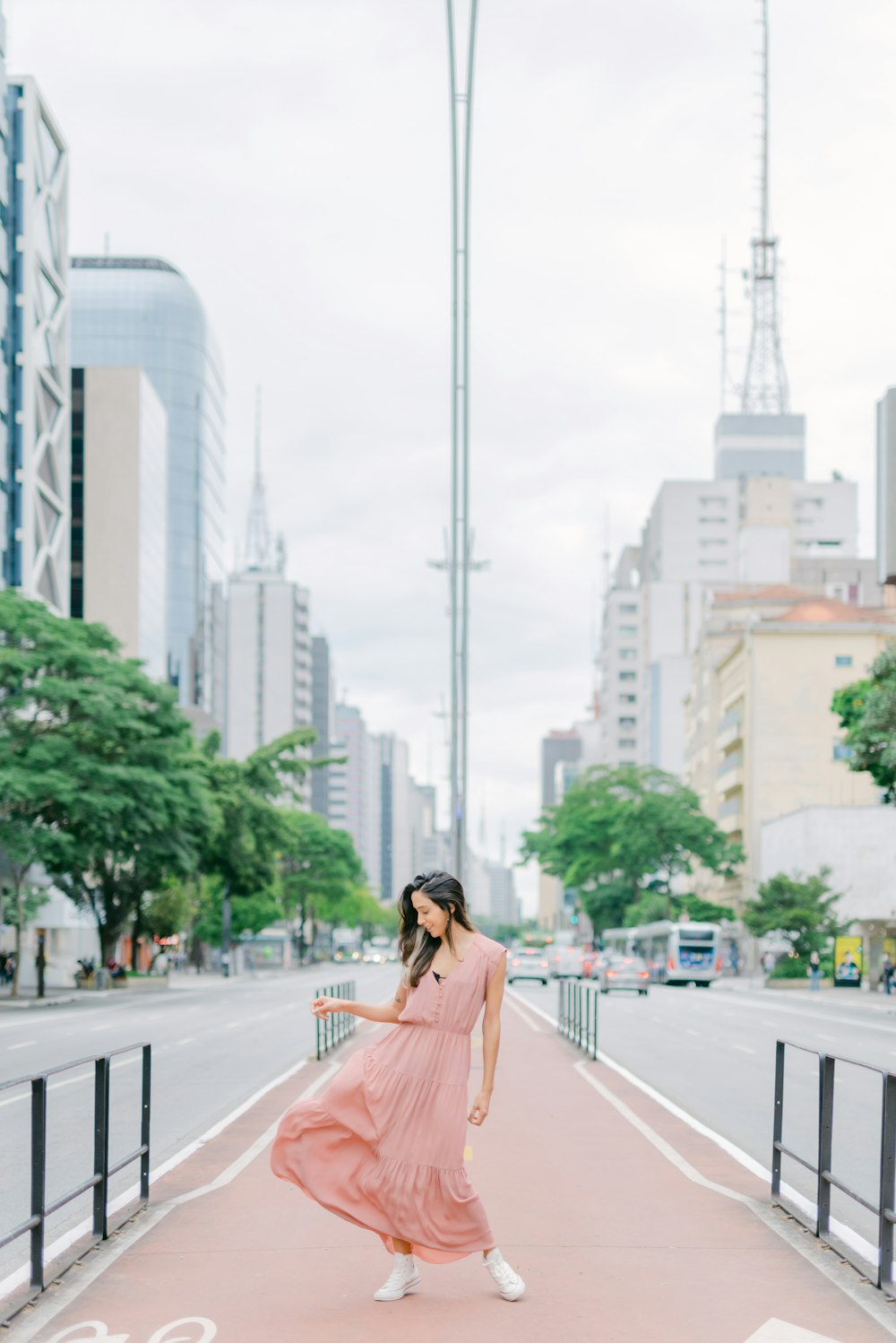 a woman in a pink dress walking down a sidewalk
