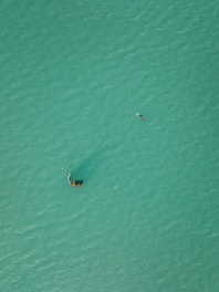 Dynamic drone footage capturing a kite surfer performing tricks over turquoise water.