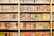 A bookshelf filled with numerous manga volumes organized neatly in rows. Each book is vividly colored, featuring different styles of artwork typical of Japanese manga. The spines display a variety of titles, characters, and symbols, creating a lively and engaging visual experience.
