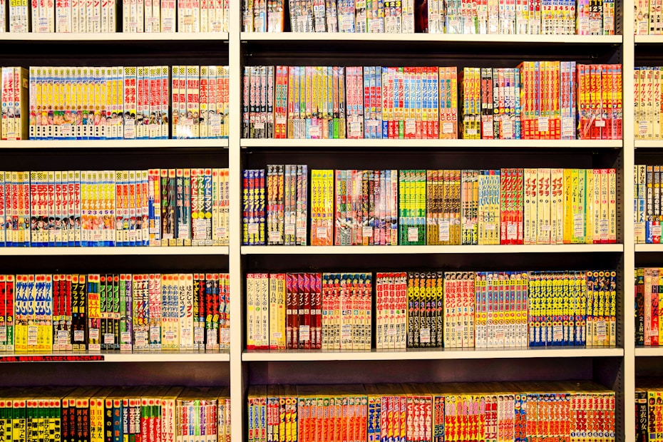 A bookshelf filled with numerous manga volumes organized neatly in rows. Each book is vividly colored, featuring different styles of artwork typical of Japanese manga. The spines display a variety of titles, characters, and symbols, creating a lively and engaging visual experience.