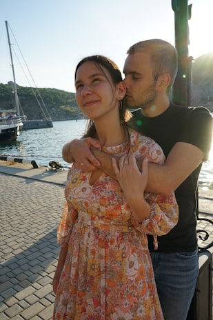 A happy couple stepping off their boat onto a wooden dock beside a vibrant seaside villa.